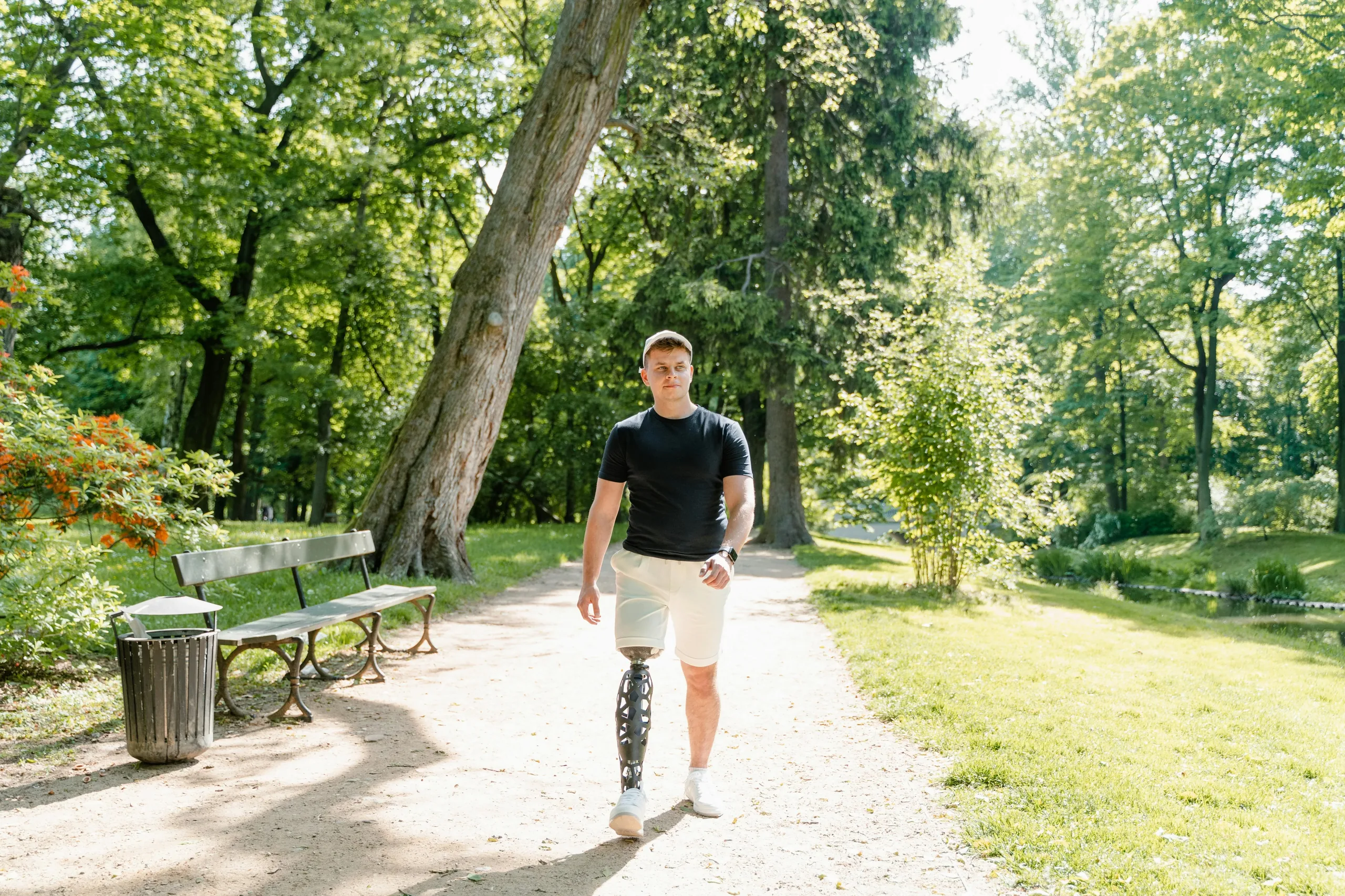 Person with a lower-limb prosthesis walking through a park
