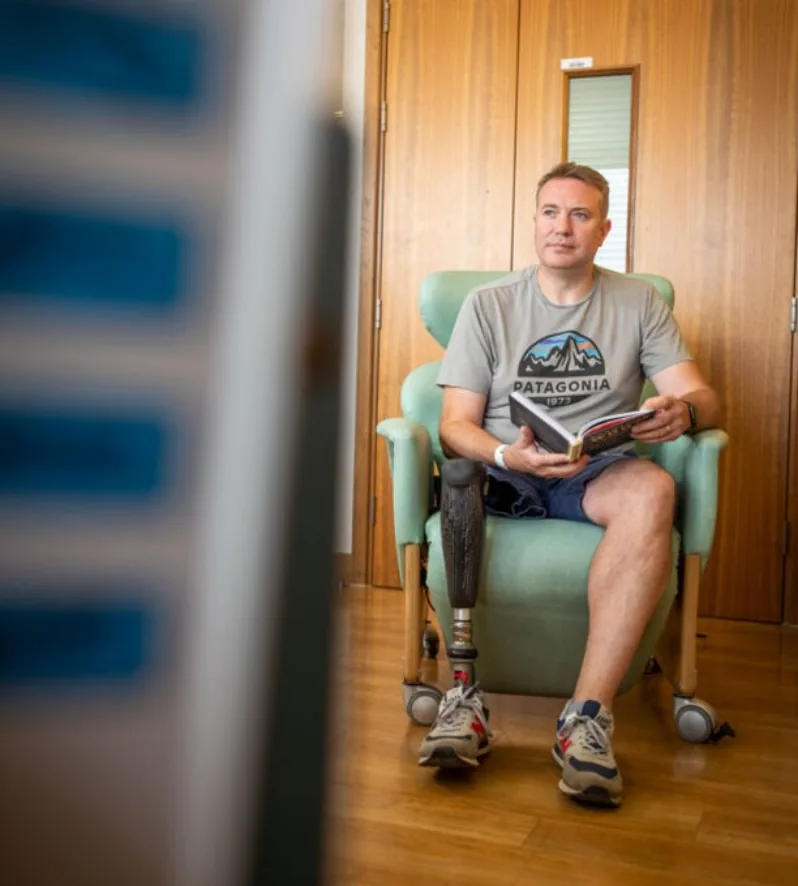 Lower-limb prosthetic user reading while seated